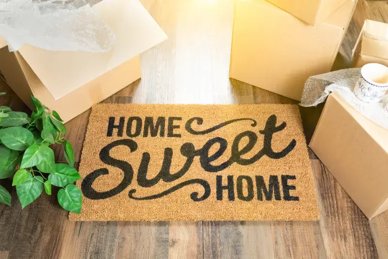 vecteezy_home-sweet-home-welcome-mat-and-moving-boxes-on-hard-wood-floor_16444465